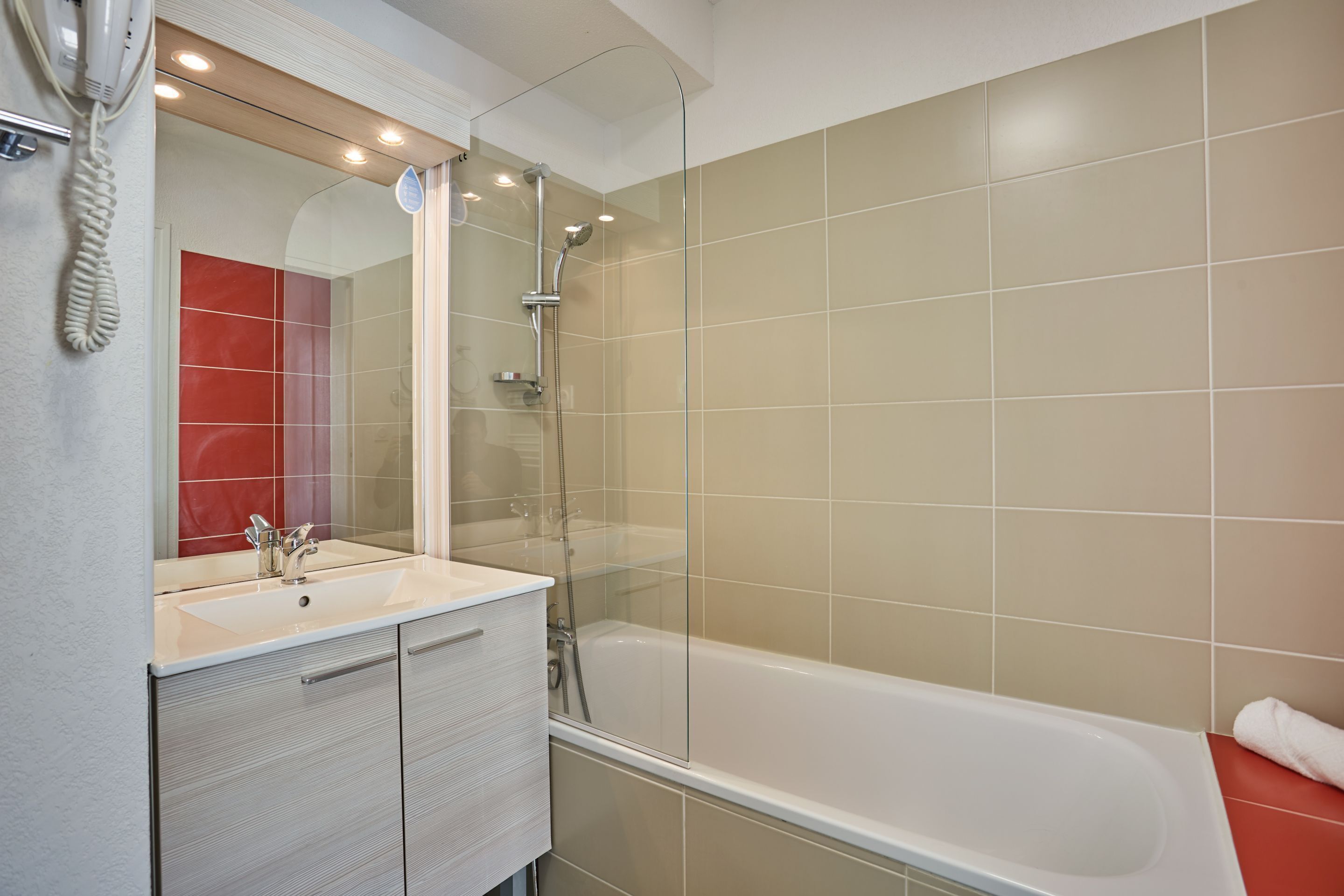 Ein modernes Badezimmer mit einer Duschkabine, einem weißen Waschbecken mit Spiegel und einer Badewanne.