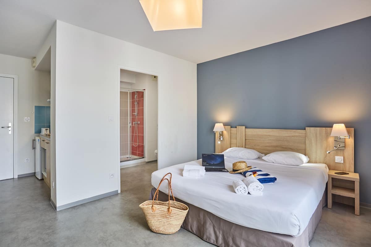 Ett modernt hotellrum med en stor säng, sänglampor, en bärbar dator och en korg av rotting.