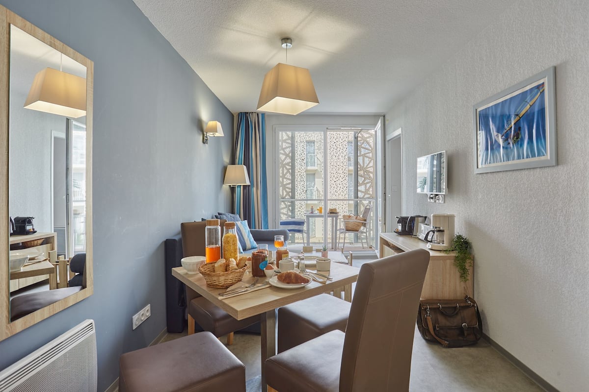 Ett modernt hotellrum med en matplats, ett stort fönster med utsikt, en spegel och en tavla på väggen.
