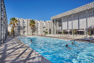 Una piscina con sillas de descanso y palmeras.