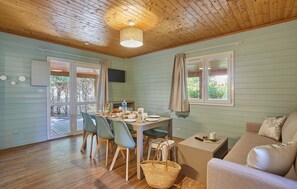 A dining area with a table set for four, chairs, a basket, a sofa, and a TV mounted on the wall.