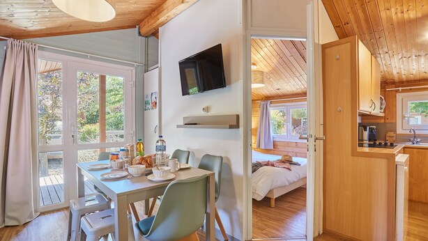 A cozy cabin with a dining area, a TV mounted on the wall, and a kitchen. - Résidence Odalys Shangri-La - Les Hauts de Cassis (Carnoux-en-Provence)