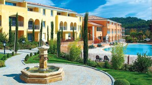 A hotel with a swimming pool, a fountain, and a landscaped garden.