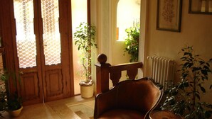 A room with a wooden chair, a small table, and potted plants. - Locanda Modigliani (Ferrara)