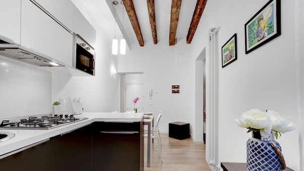 A modern kitchen with a central island, white cabinetry, and a wooden ceiling.