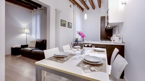 A dining area with a table set for four, a sofa, and a kitchen in the background.