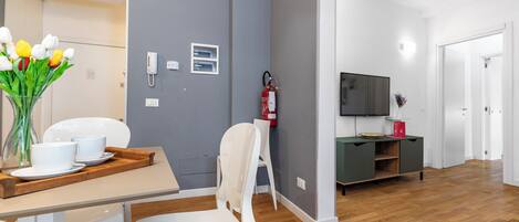 Un salon moderne comprenant un coin repas, un téléviseur à écran plat et un extincteur fixé au mur.