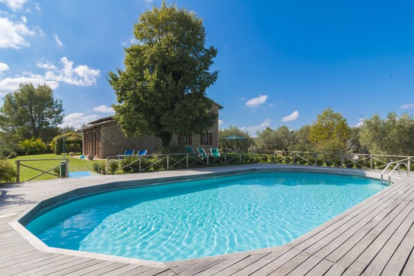 Una piscina al aire libre de temporada, sombrillas