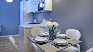 Una cocina moderna con armarios blancos, horno integrado y comedor con mesa lista para cuatro.