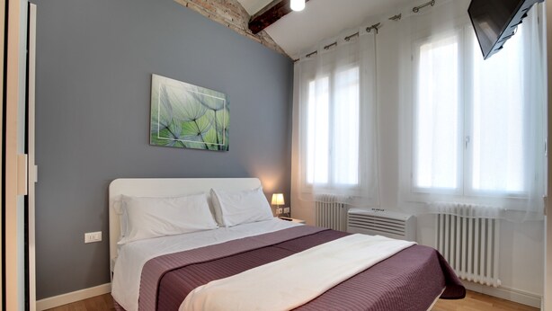 Un dormitorio con una cama grande, un cuadro en la pared y una ventana con cortinas.