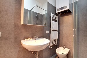 A modern bathroom with a large sink, a bidet, a glass shower enclosure, and a towel rack. - Ca dei Botteri 4 (Venice)