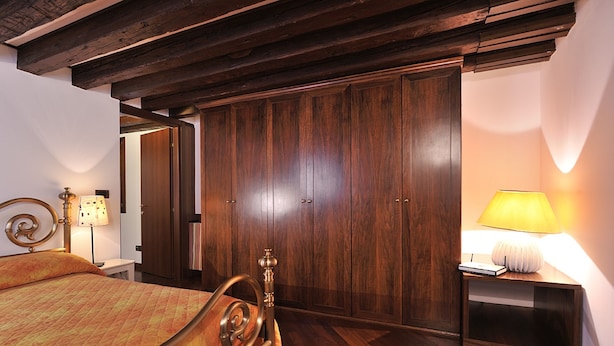 Un dormitorio con una cama de madera, un armario y una mesita de noche con una lámpara.