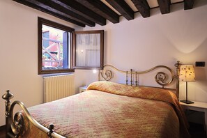 A bedroom with a bed, a window, a bedside table with a lamp, and a radiator. - Ca dei Dai (Venice)