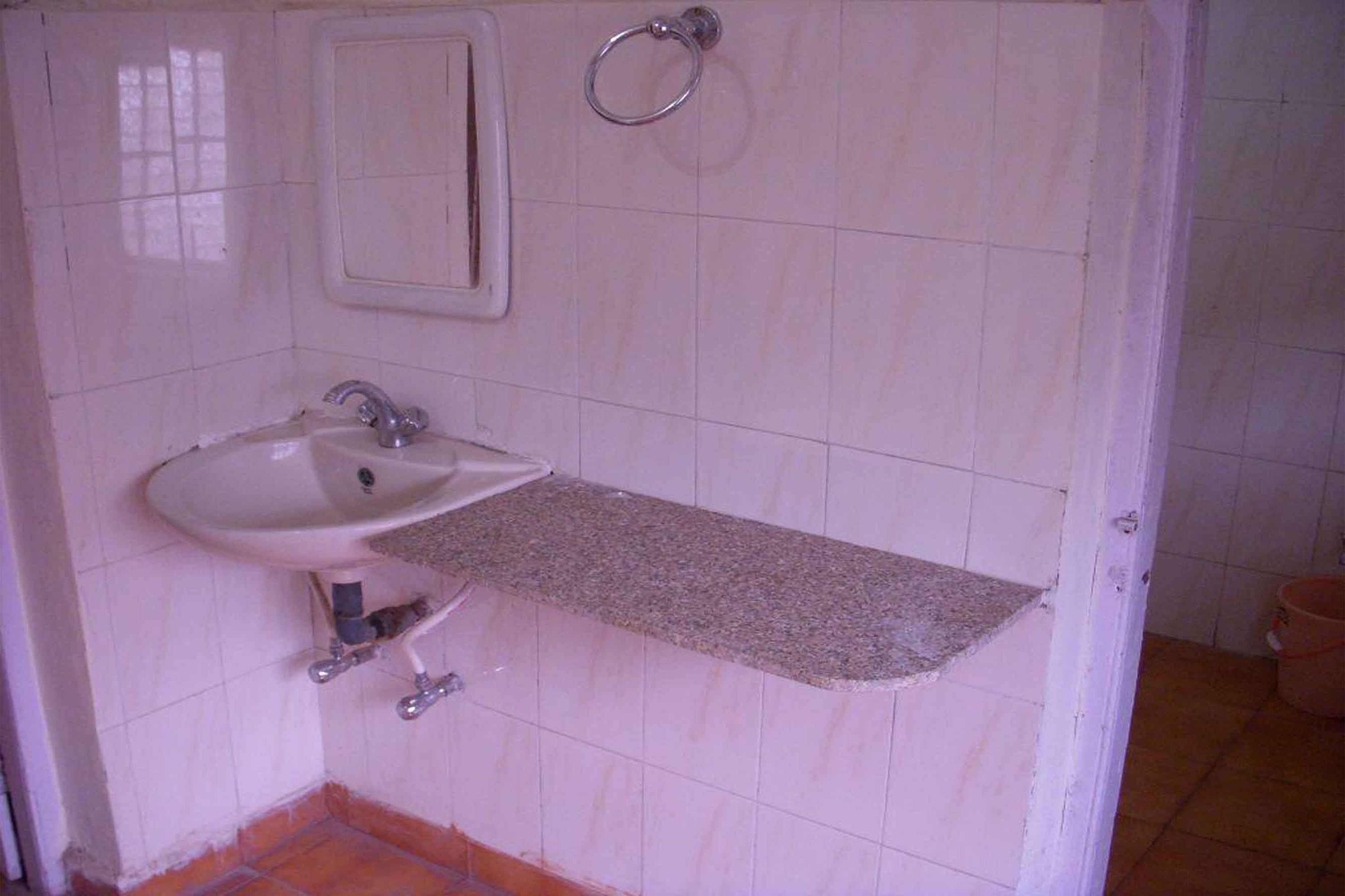 A bathroom with a white sink, a mirror, and a towel ring.