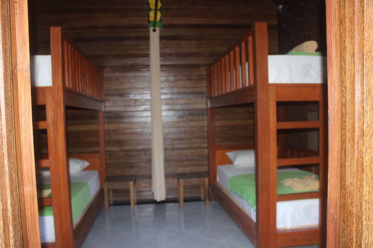 A room with two bunk beds, wooden walls, and a simple layout.
