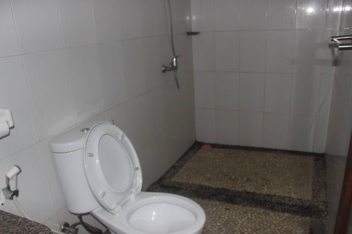 A bathroom with a toilet, a shower, and a tiled floor.