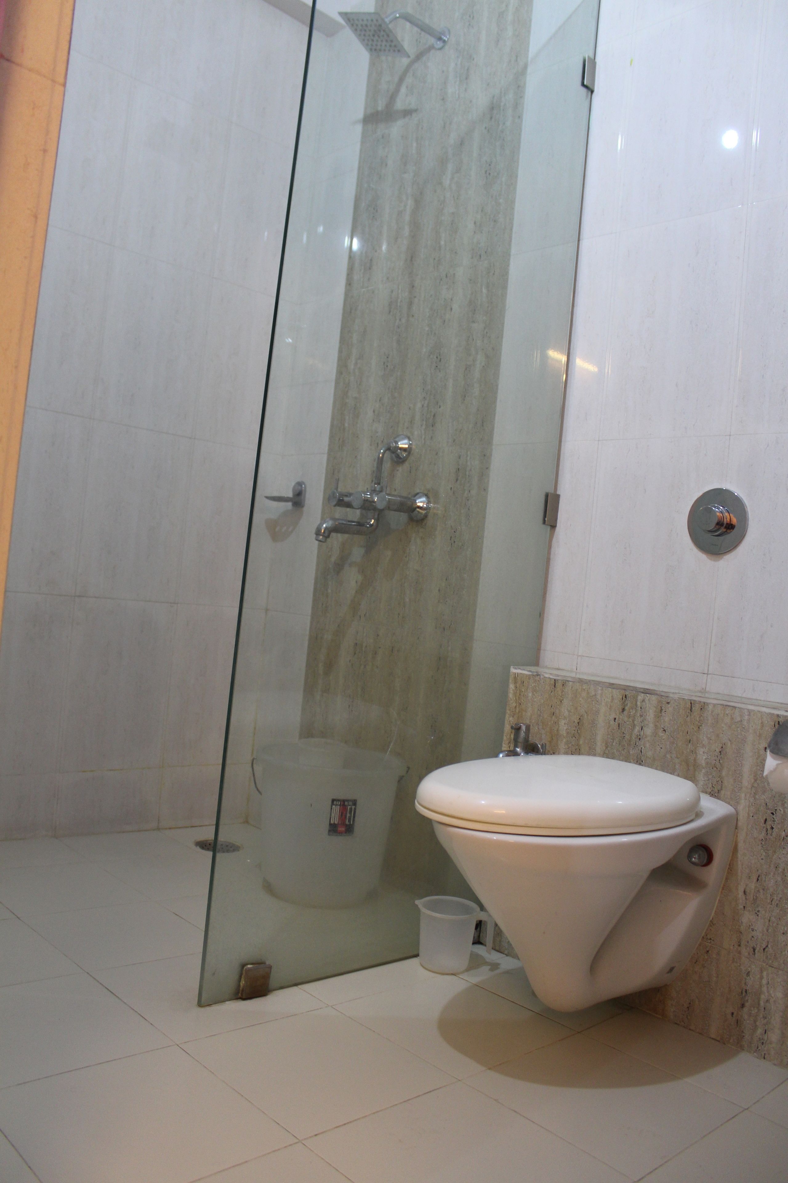 Un baño con ducha corredera de vidrio, inodoro y lavamanos.