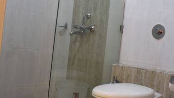 Un baño con ducha corredera de vidrio, inodoro y lavamanos.