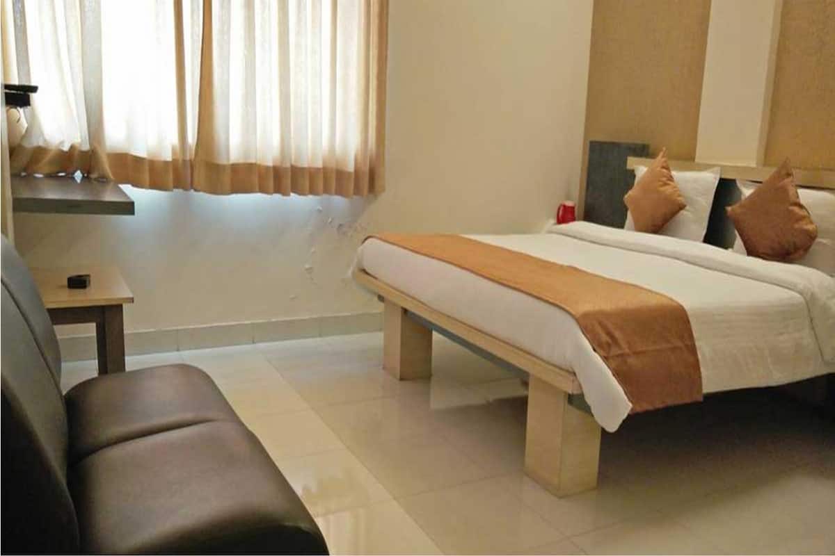 A hotel room with a bed, a bench, a small table, and a sofa.