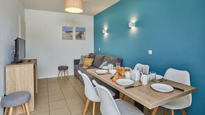 Un espace de salle à manger moderne avec une table en bois, des chaises blanches et un mur d’accent bleu.