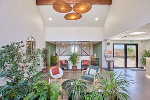 A spacious lobby with comfortable seating, a large potted plant, and a reception desk. - Résidence Odalys Domaine des Côteaux de Sarlat (Sarlat-la-Canéda)