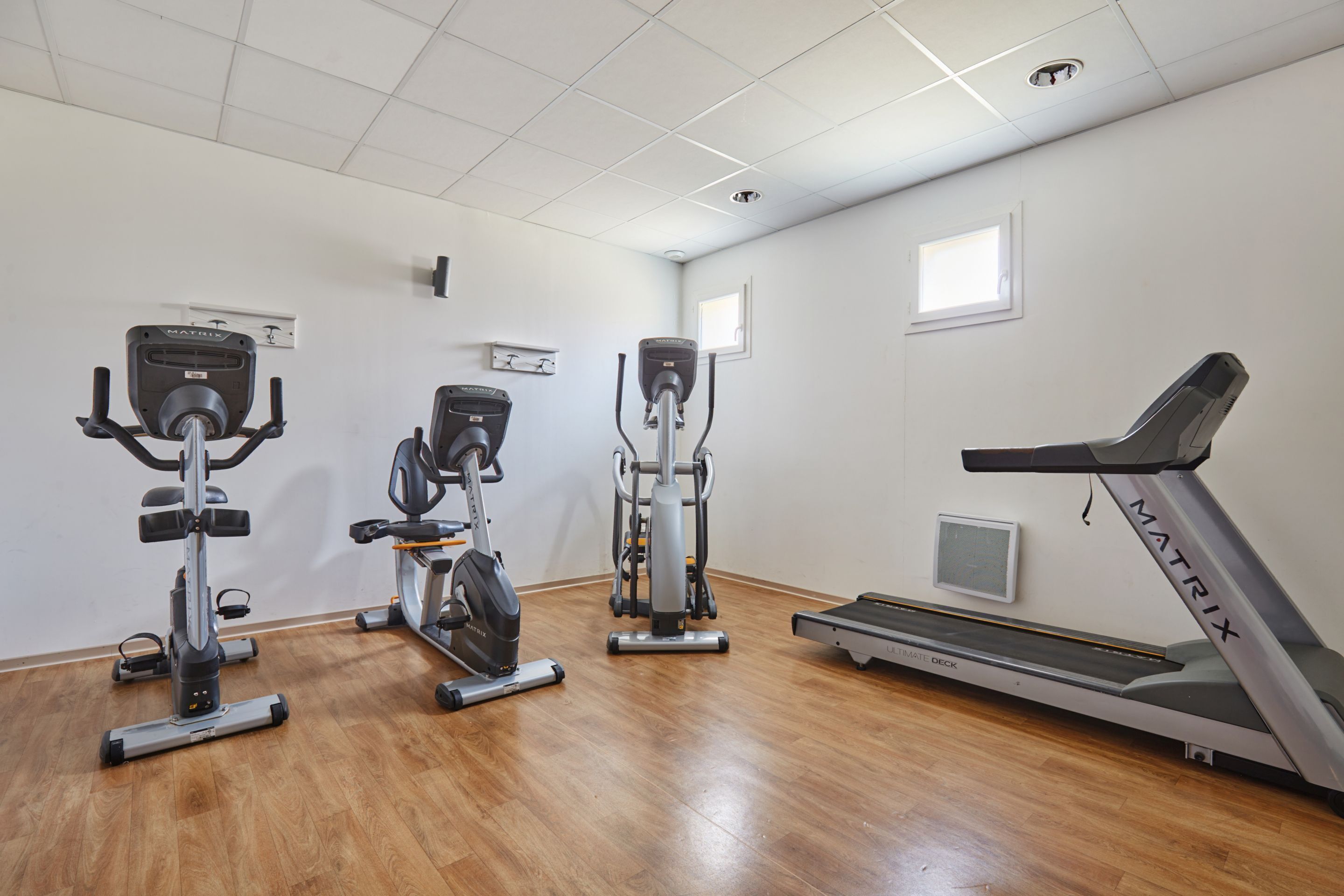 A gym with three stationary bikes, a treadmill, and a rowing machine.
