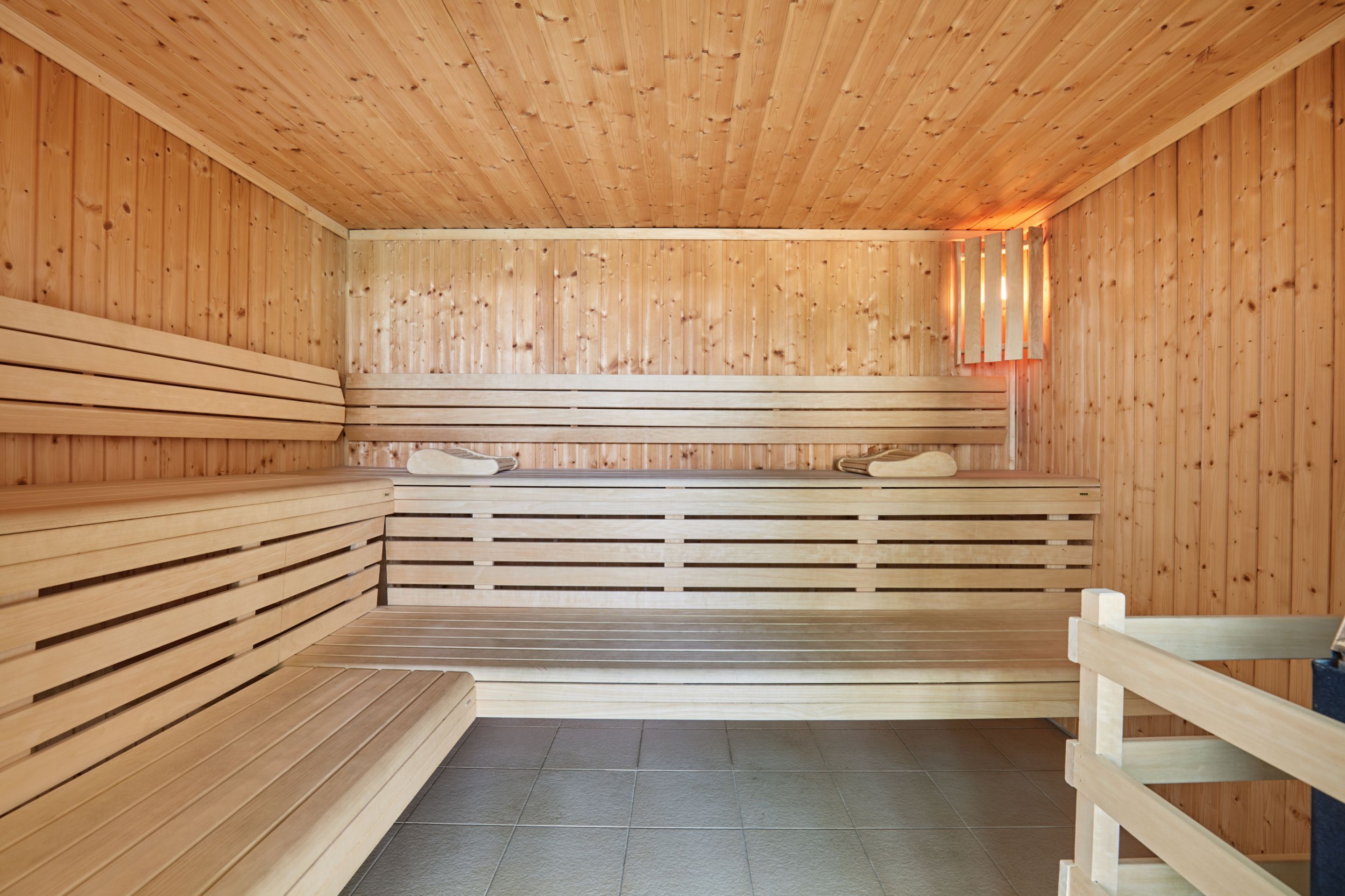 Un sauna avec des bancs en bois, un sol carrelé et un plafond en bois.
