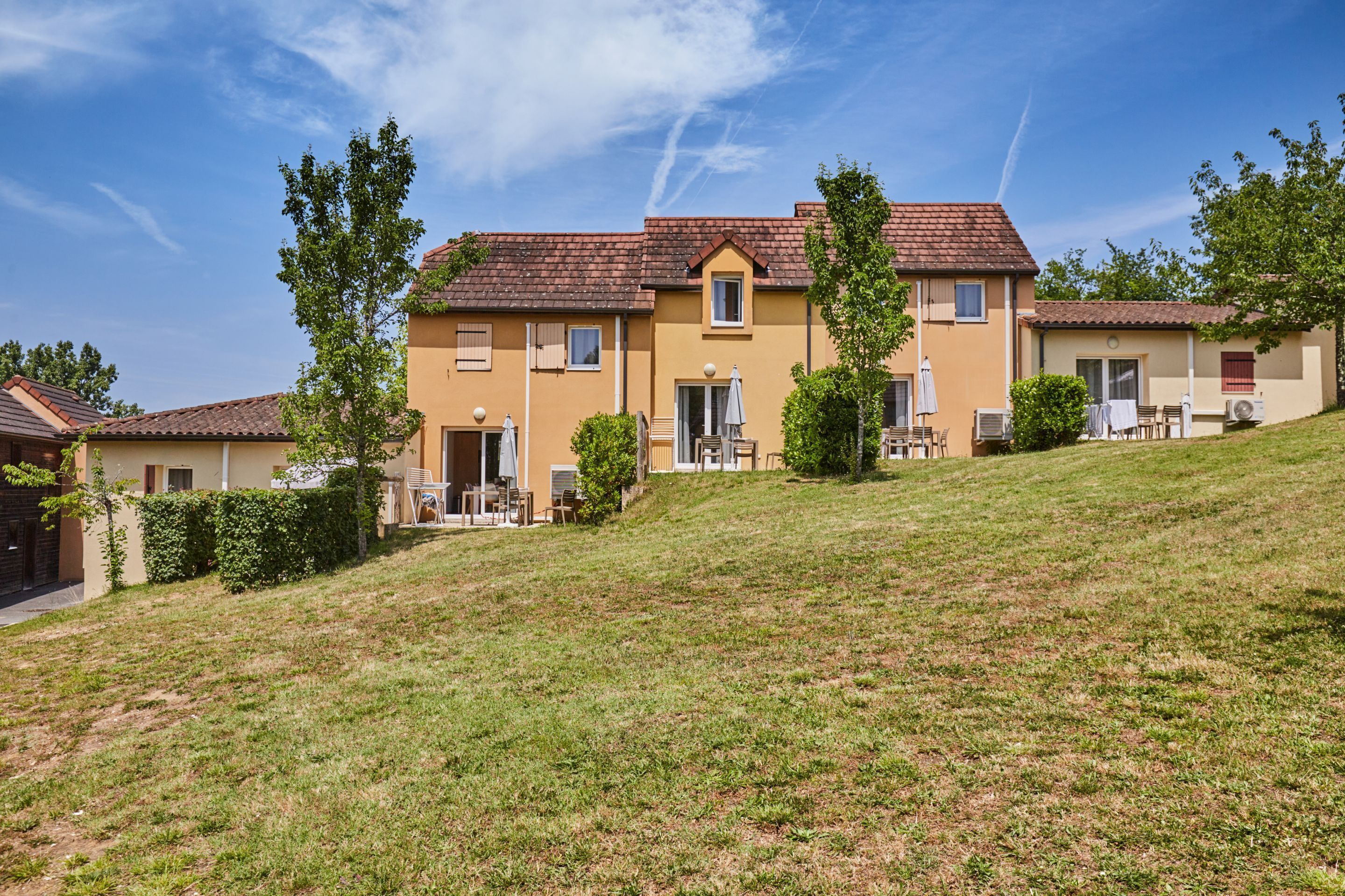 A two-story house with a sloped roof, a small porch, and a grassy yard.