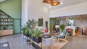 Un vaste espace intérieur doté d’un haut plafond, de meubles modernes et de nombreuses plantes.