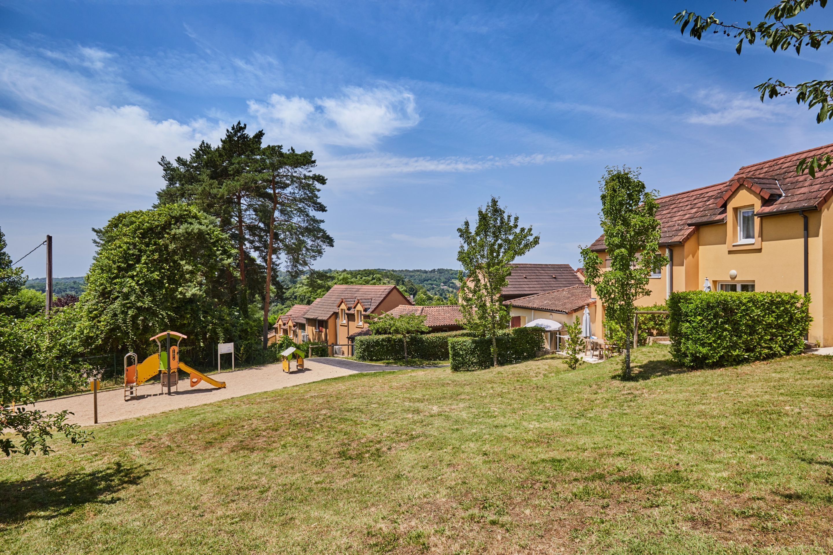 A residential area with houses, a playground, and a well-maintained lawn.