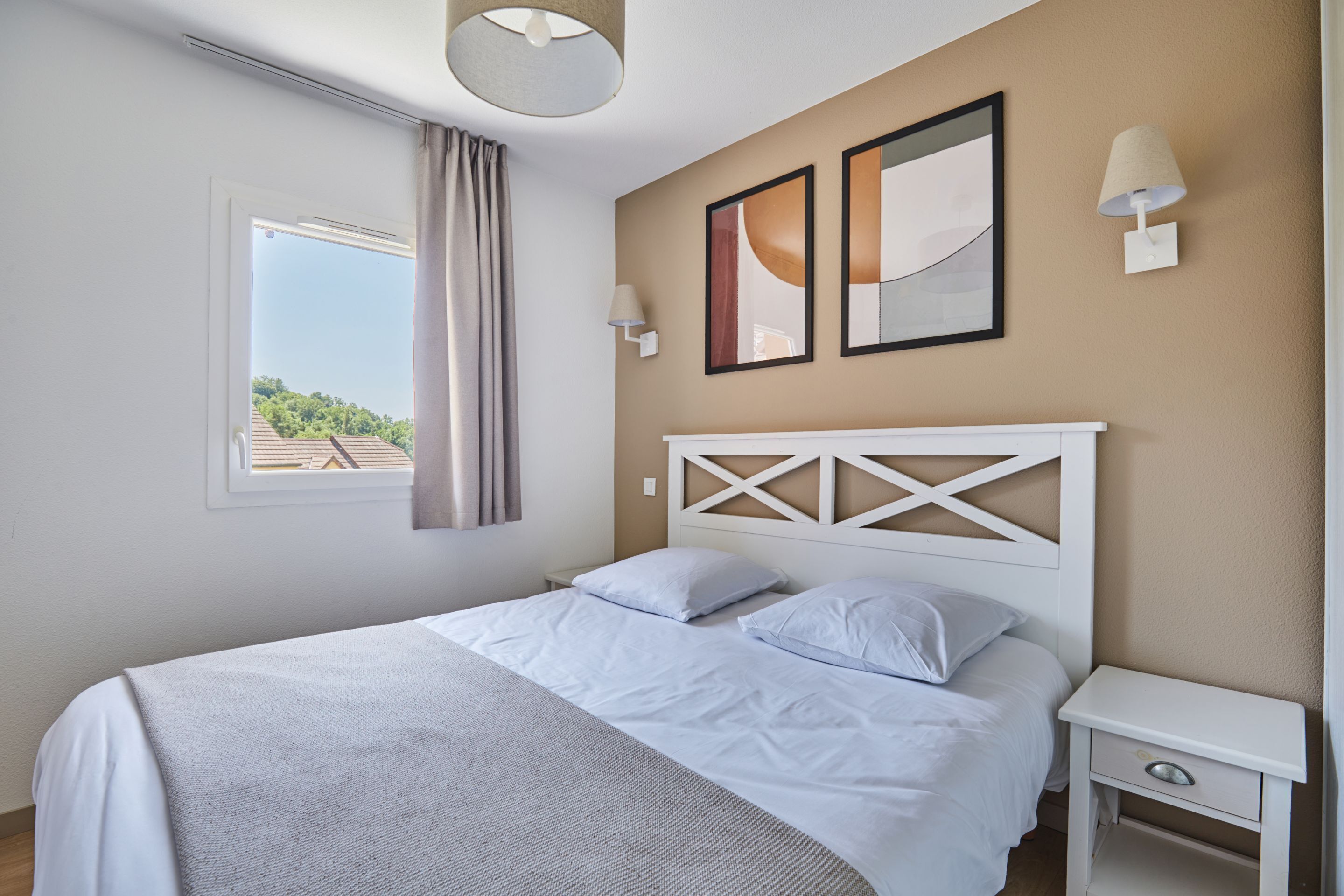 Un dormitorio ordenado con una cama, una mesita de noche y una ventana con cortinas.