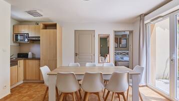 A modern kitchen with a dining area, wooden cabinets, a microwave, and a large window.