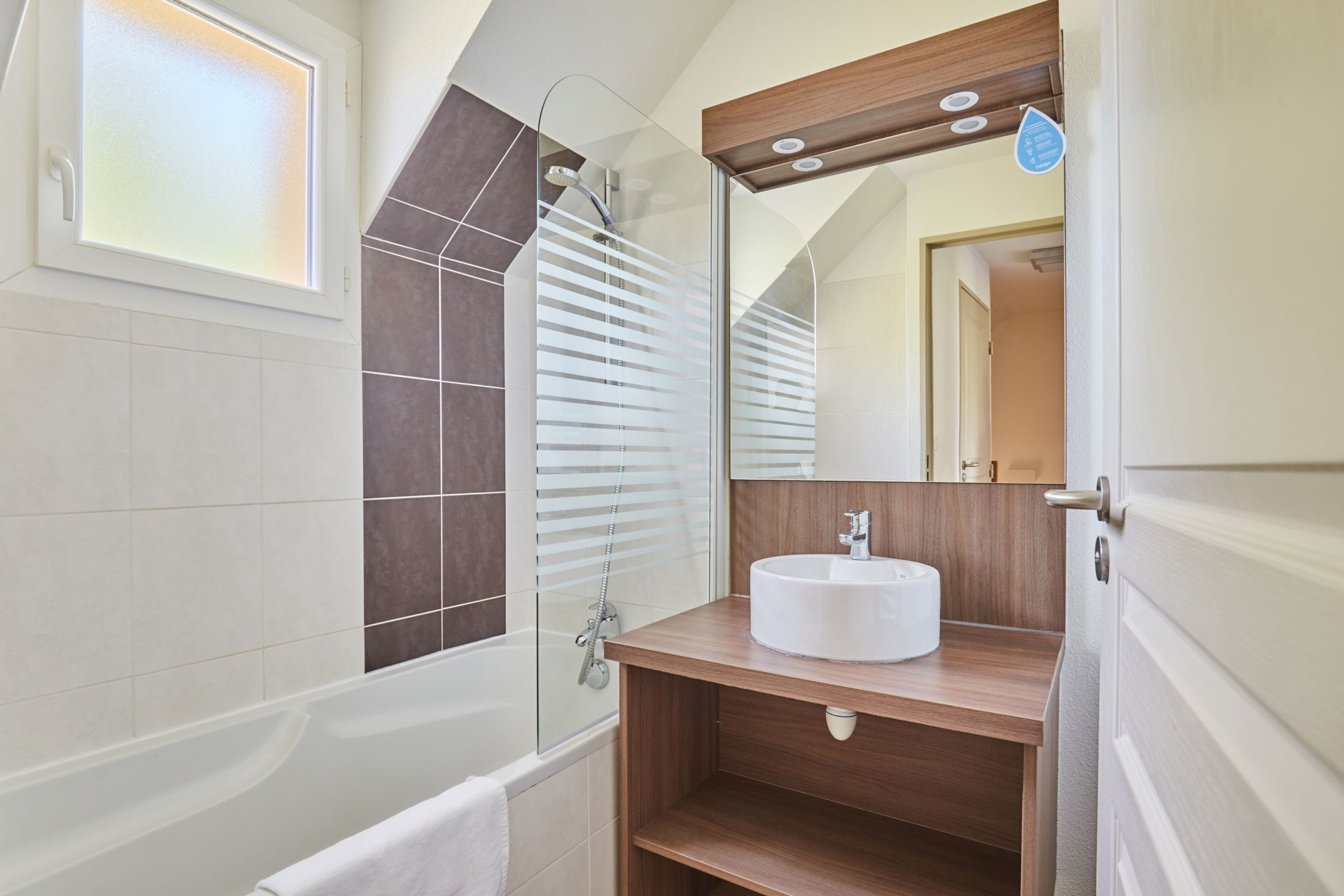 A modern bathroom with a bathtub, a glass-enclosed shower, and a wooden vanity with a sink.