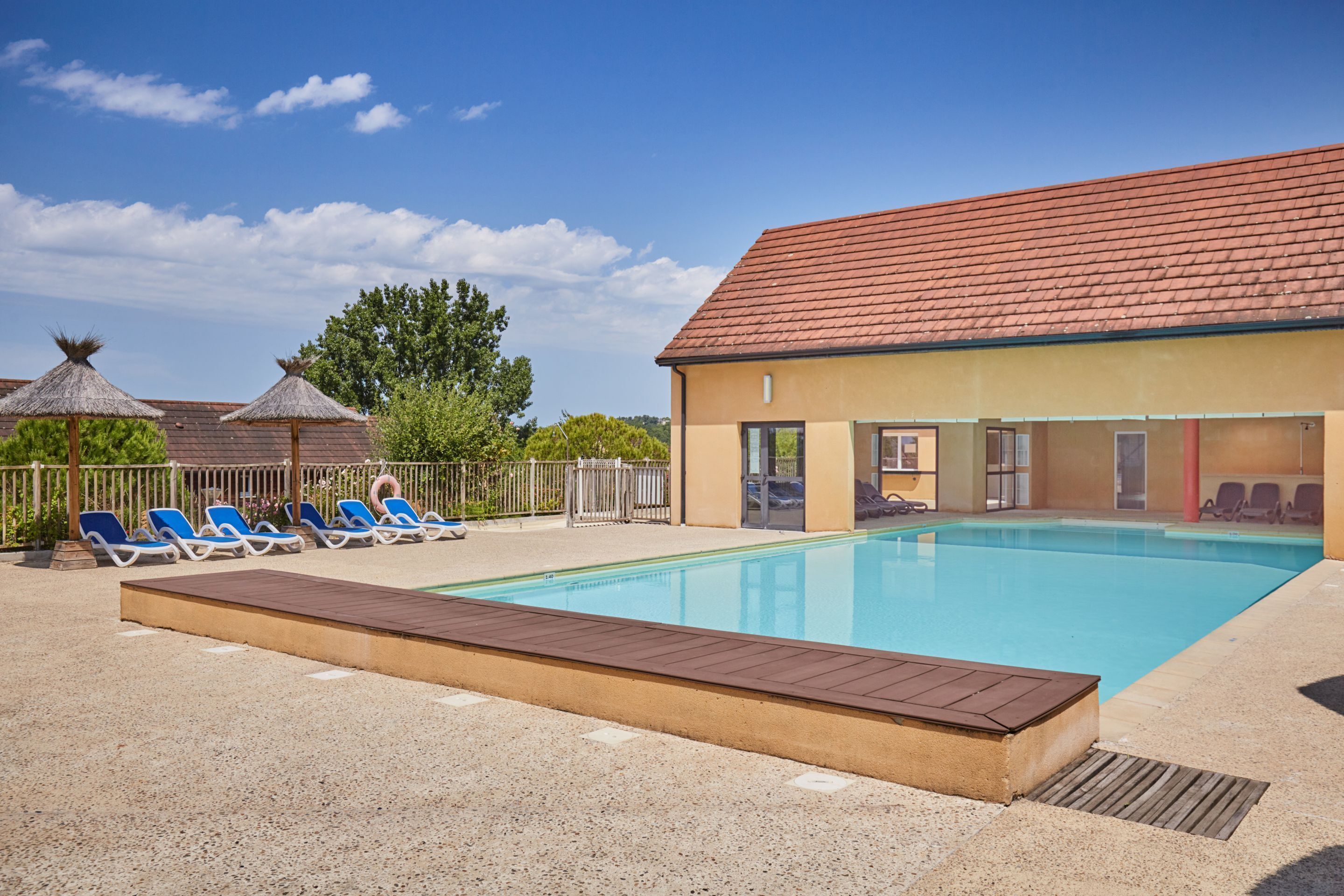 Un espace piscine avec des chaises longues et une terrasse en bois.