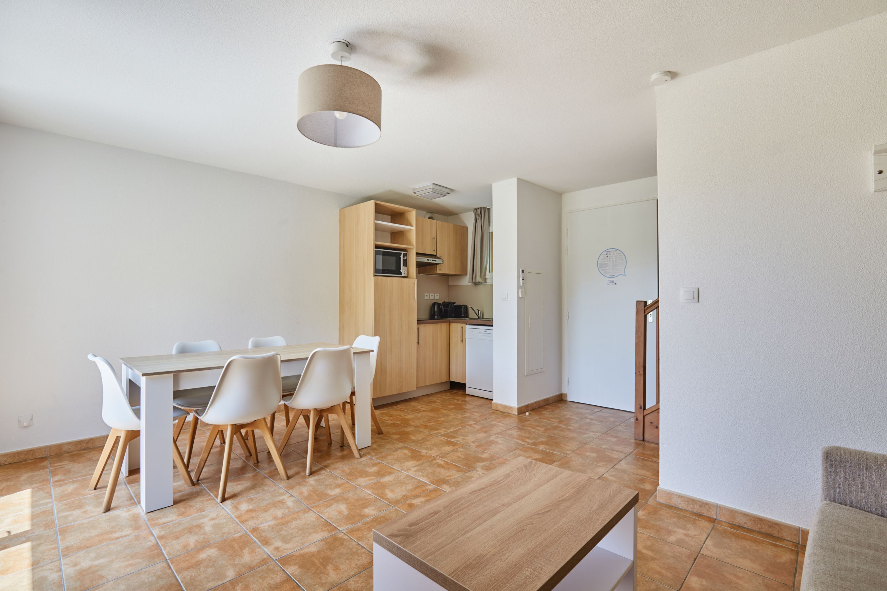 Una cocina moderna con una mesa de comedor, sillas, microondas y lavavajillas.