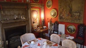 A dining room with a fireplace, a table set for four, and a painting on the wall. - Beggar's Knap (Dorchester)