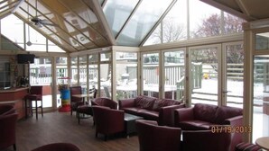 A sunroom with large windows, leather sofas, and a small table. - Beggar's Knap (Dorchester)