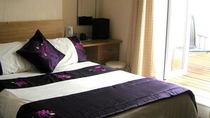 Habitación de hotel con cama, escritorio, silla, televisor y vistas al exterior.
