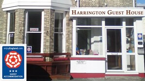 Un edificio de dos pisos con un cartel que dice 'Harrington Guest House'.
