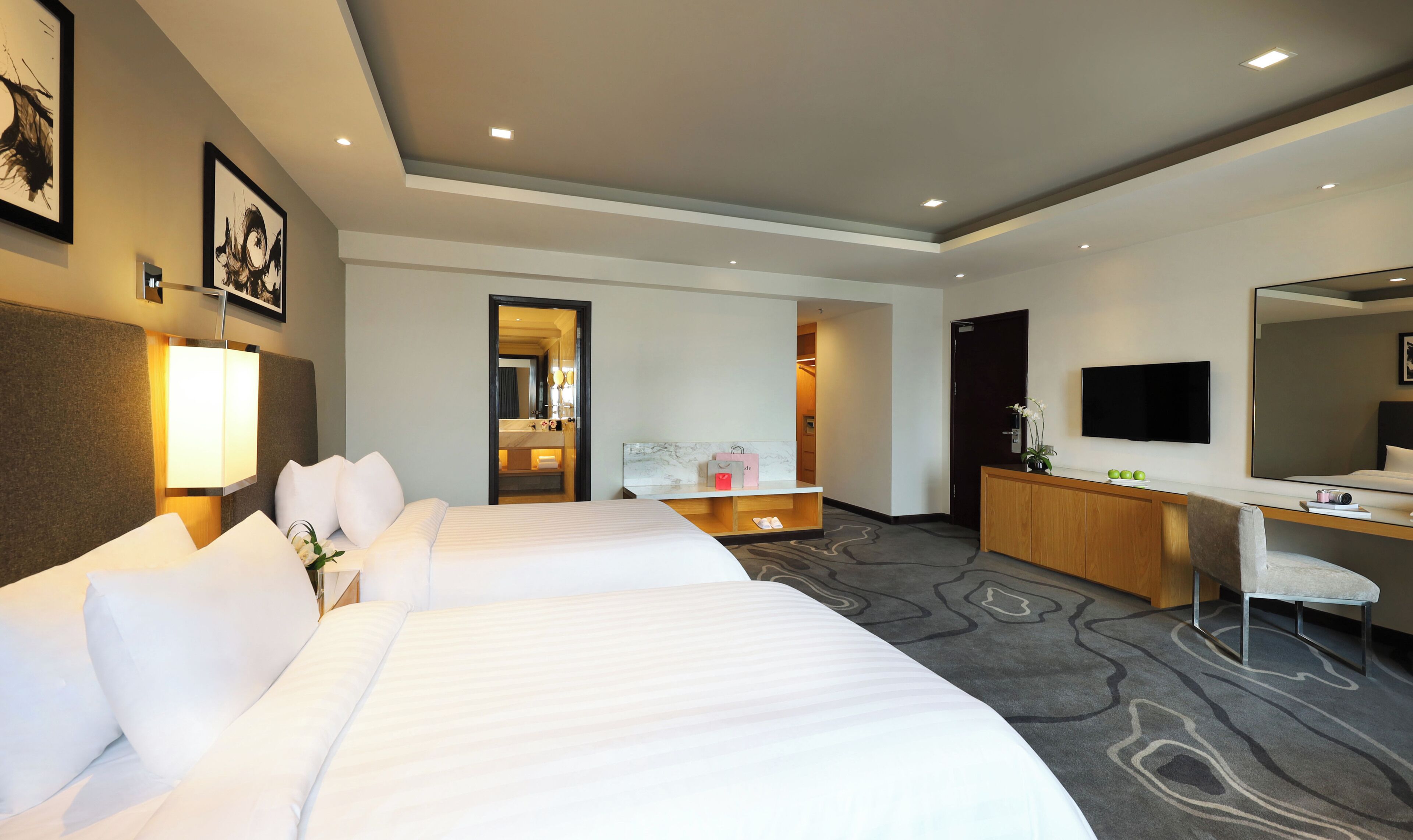 A hotel room with a large bed, a desk, a chair, a TV, and a mirror.