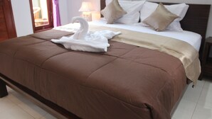 Habitación de hotel con una cama grande, una toalla con forma de cisne y una ventana con cortinas.