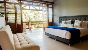 A bedroom with a bed, a sofa, and a balcony with a view of greenery. - La Herencia Hotel (Armenia)