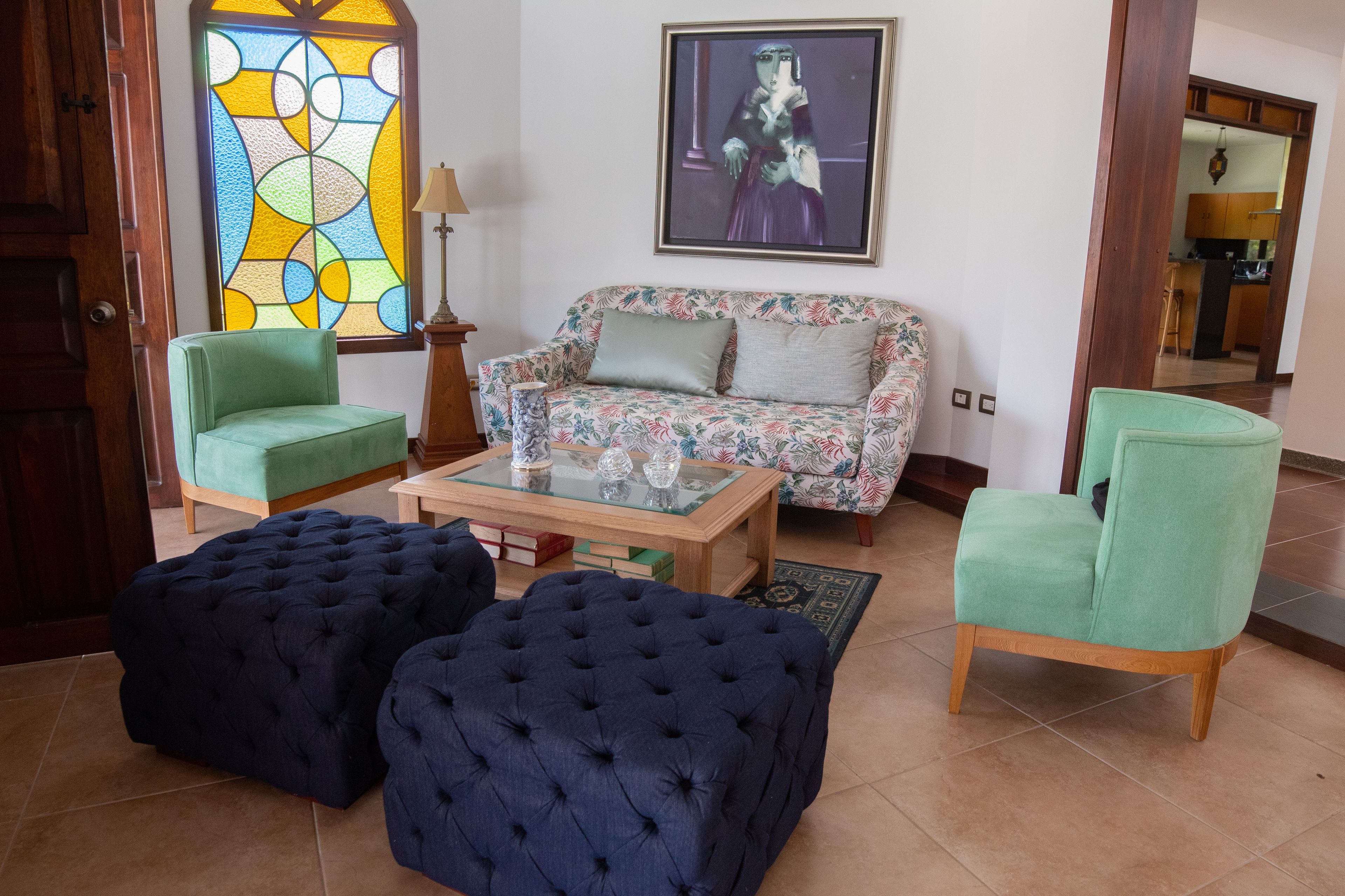 Una sala de estar con un sofá, dos sillones, una mesa de centro y un ventanal con vitrales.