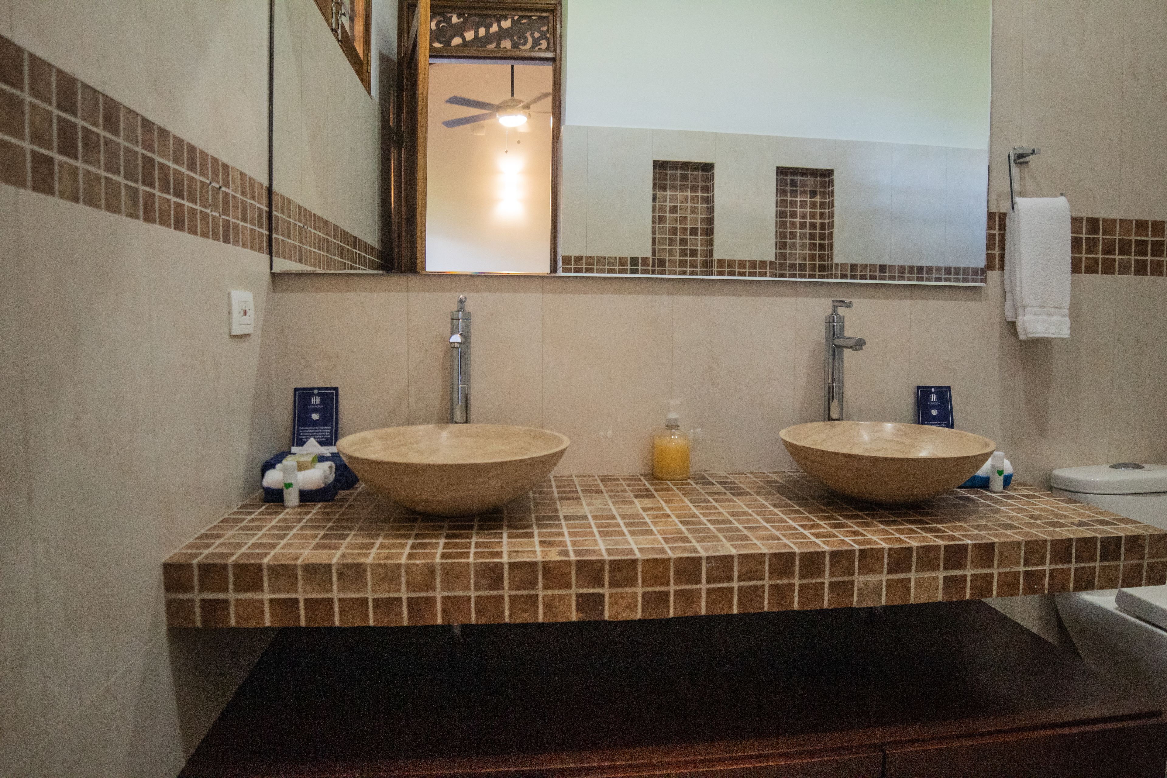 A bathroom with two sinks, a mirror, and a toilet.