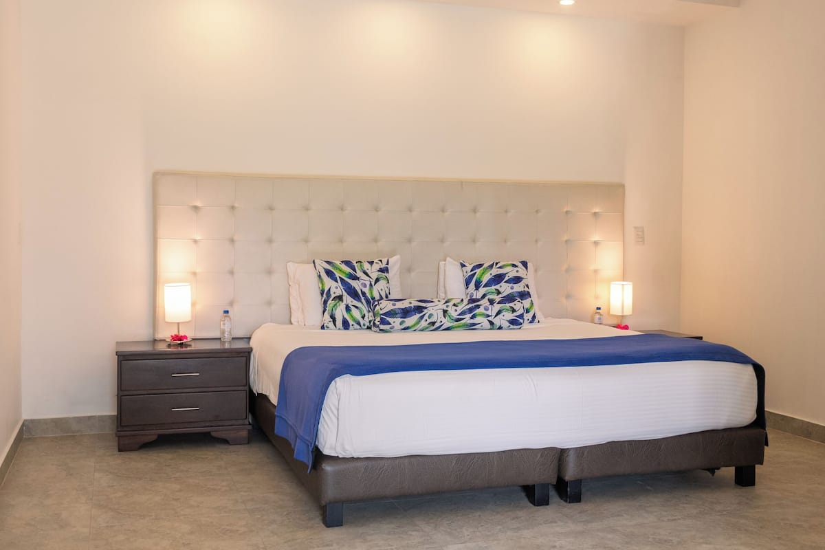 A neatly arranged bedroom with a large bed, two bedside tables, and a headboard with integrated lighting.