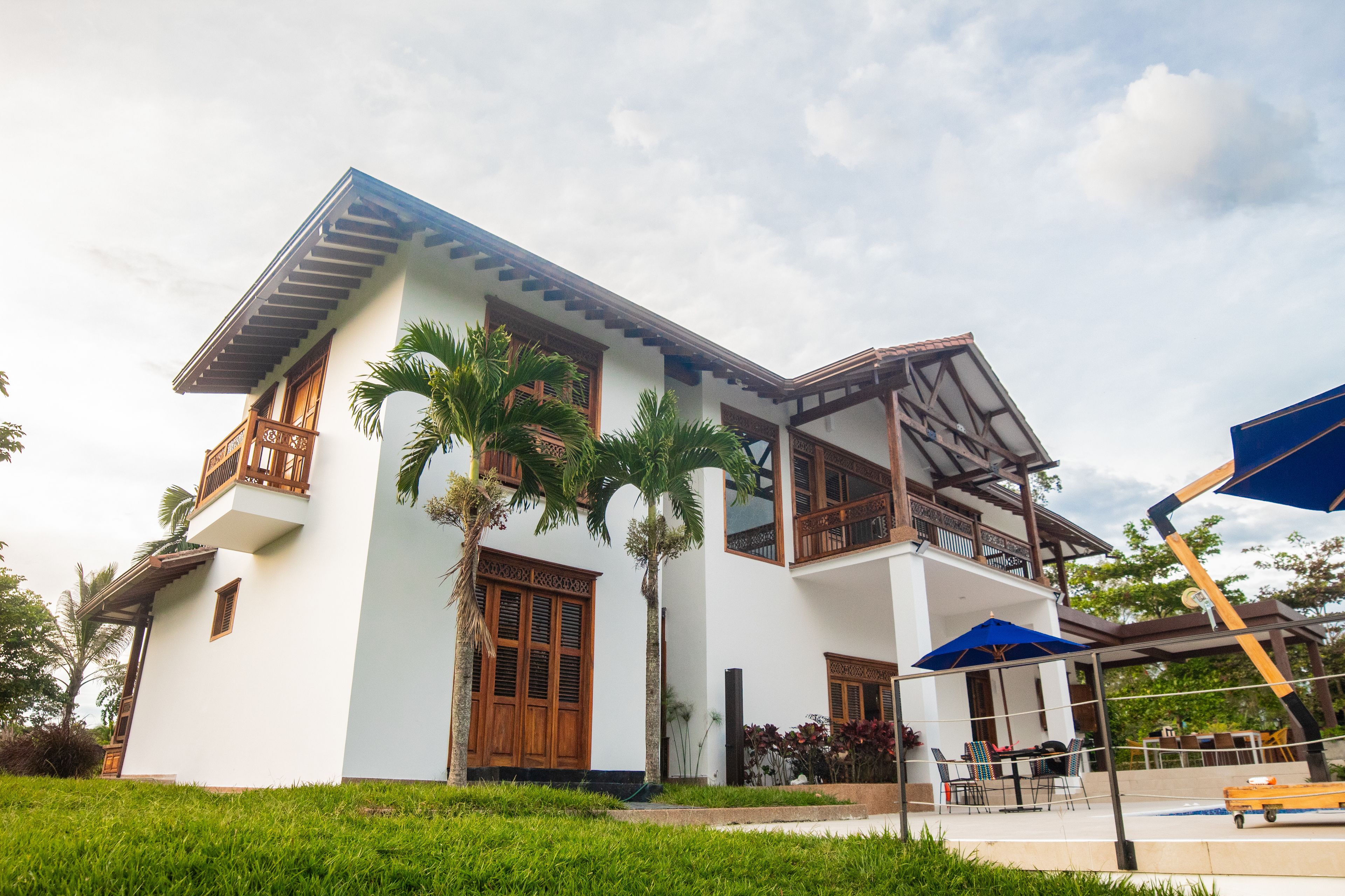 A two-story building with a balcony, wooden doors, and a covered outdoor seating area.