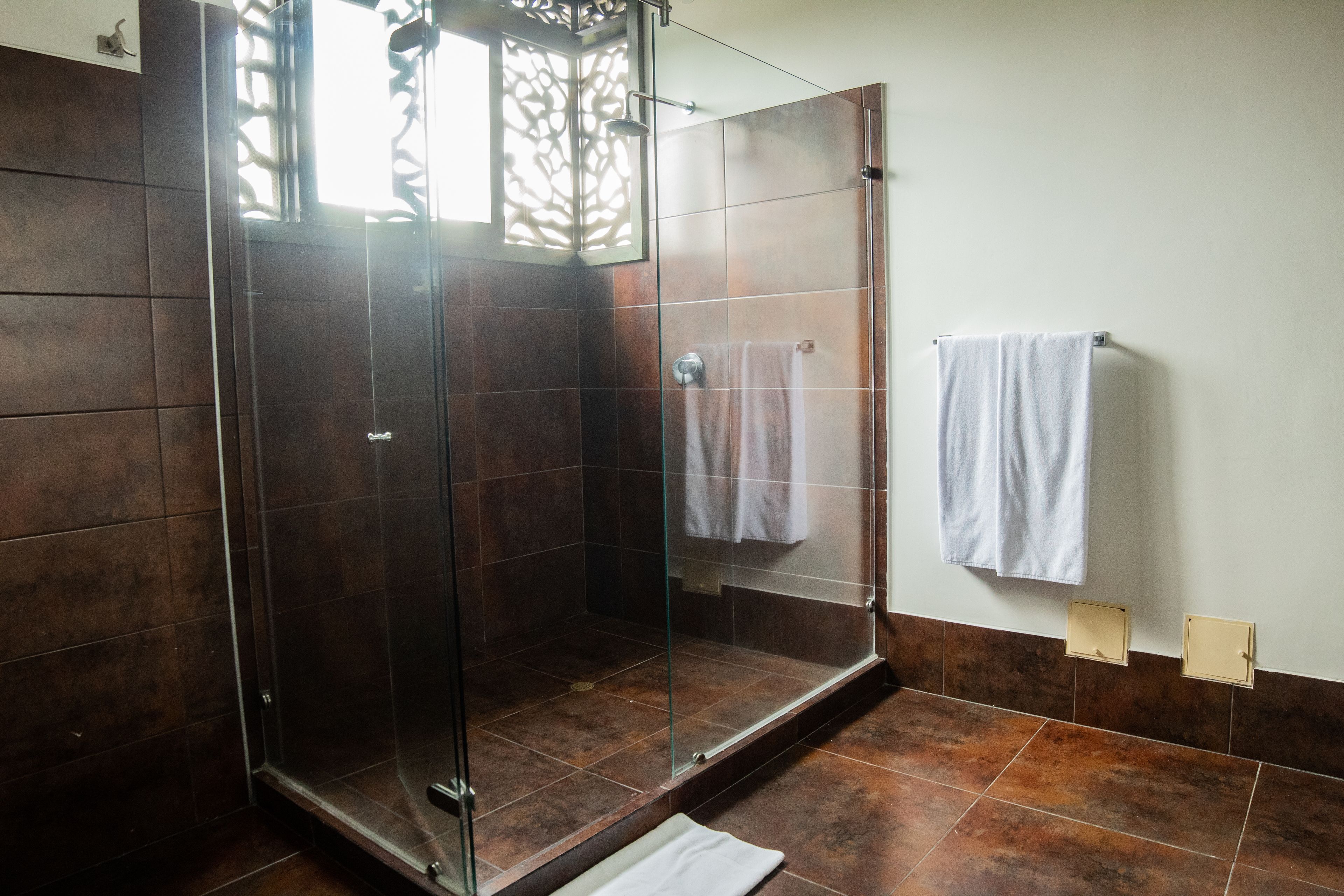 A modern bathroom with a glass-enclosed shower, tiled walls, and a white towel hanging on the wall.