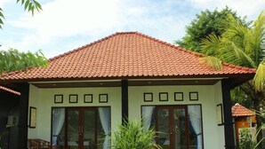Een huis met twee verdiepingen, een pannendak, grote ramen en een veranda met stoelen.