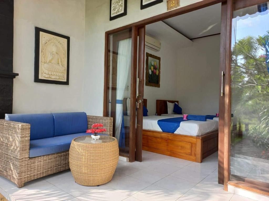 A room with a sofa, a round wicker table, and a bed with a blue and white bedspread.