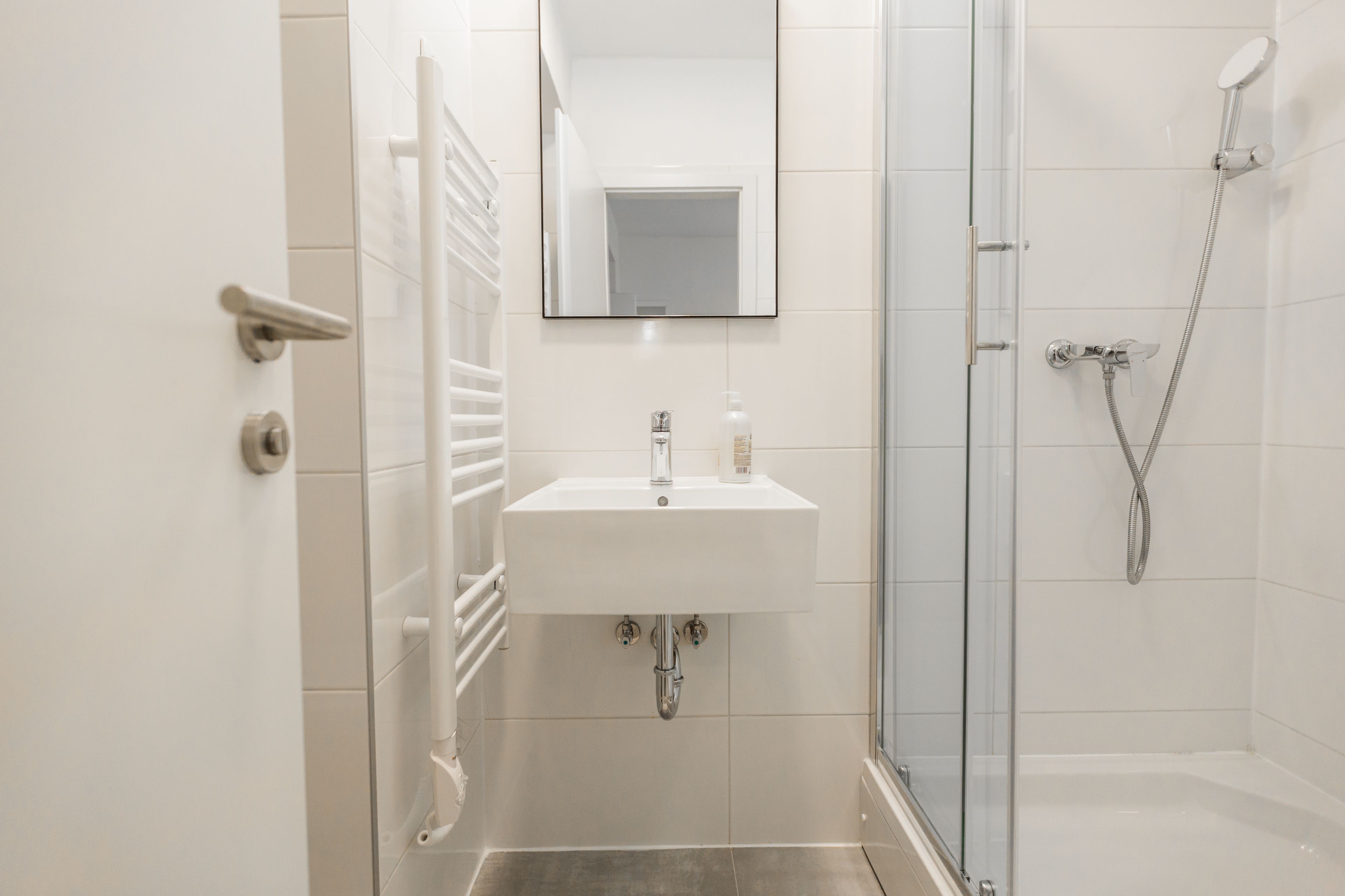 Une salle de bain moderne avec un lavabo blanc, un miroir et une douche.